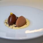 Rijks Amsterdam Two pieces of Rijks chocolate on a white plate.