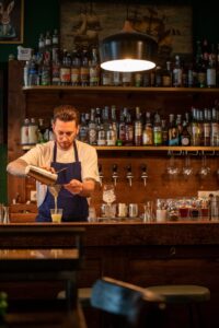 A man pouring a drink at Cambridge Public House.