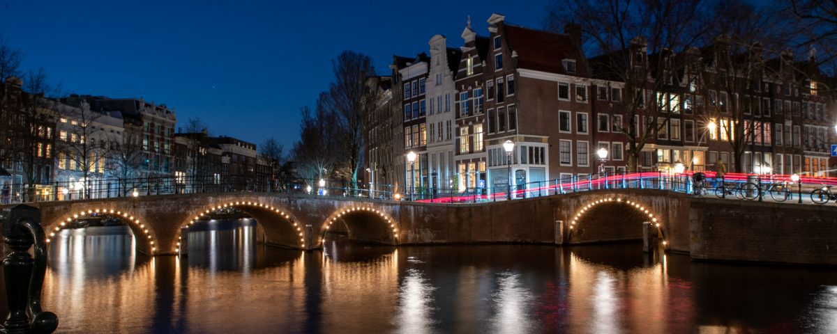A night bridge over a body of water in Amsterdam.