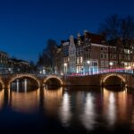 Top 17 things to do in Vibrant Amsterdam A night bridge over a body of water in Amsterdam.