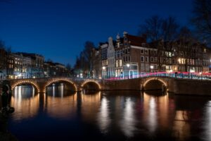 A night bridge over a body of water in Amsterdam.