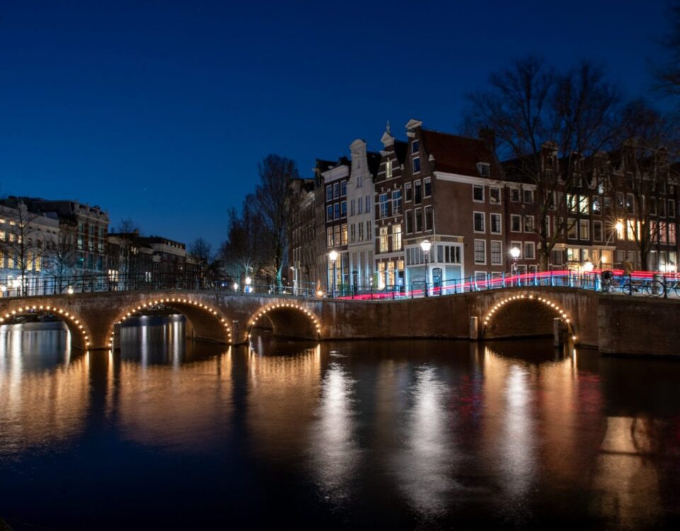 A night bridge over a body of water in Amsterdam.