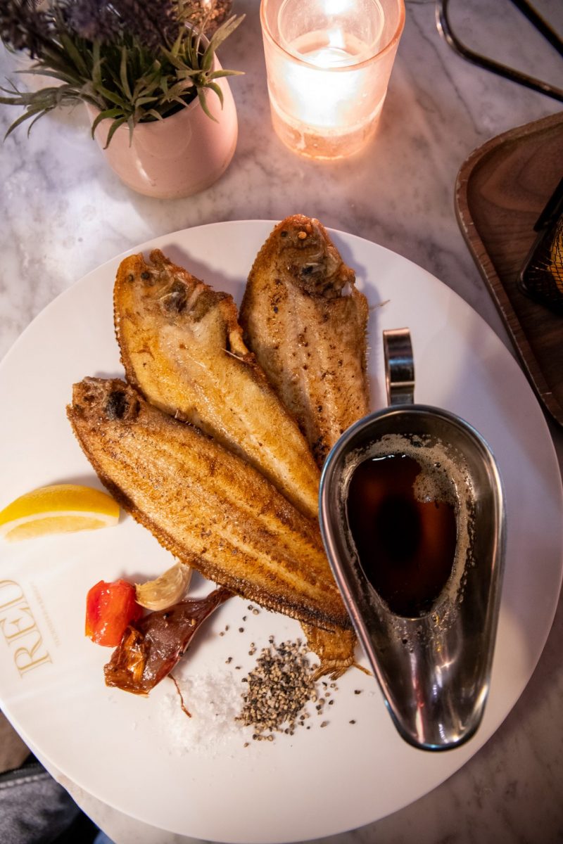 A fried fish dish with candle on a white plate in Amsterdam.