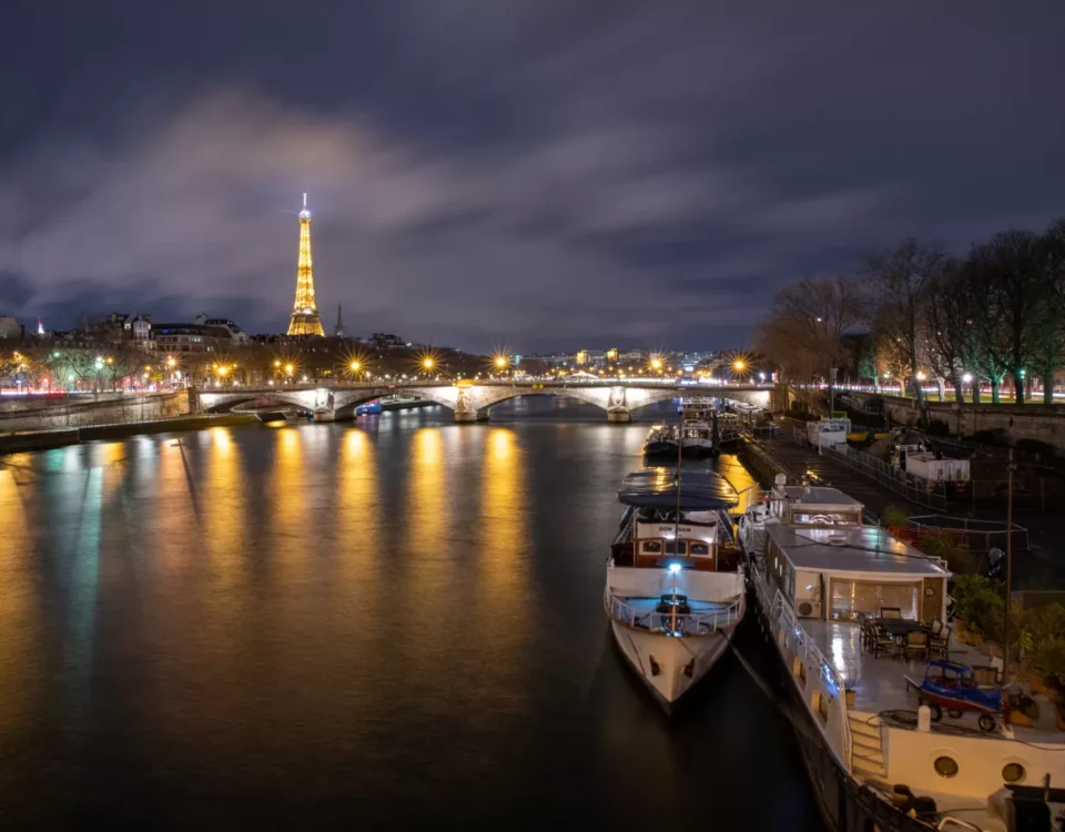 Paris from a bridge with boats and eiffel tower in the background.